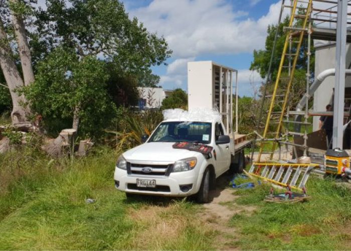 white Ute on grass at bulding site with large switchboard on the back