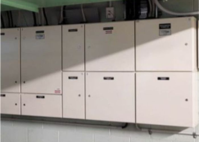 Long narrow controls switchboard in hospital basement on painted brick basement walls